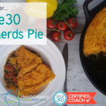 Een bord met een stuk Whole30 shepherds pie erop. De pan met precies die punt eruit staat ernaast