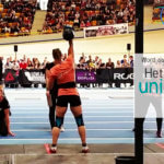 vrouw, Naomi, staat met een kettlebell van 24 kilo met rechterarm compleet uitgetrekt boven haar hoofd. op de achtegrond zie je publiek in het stadion